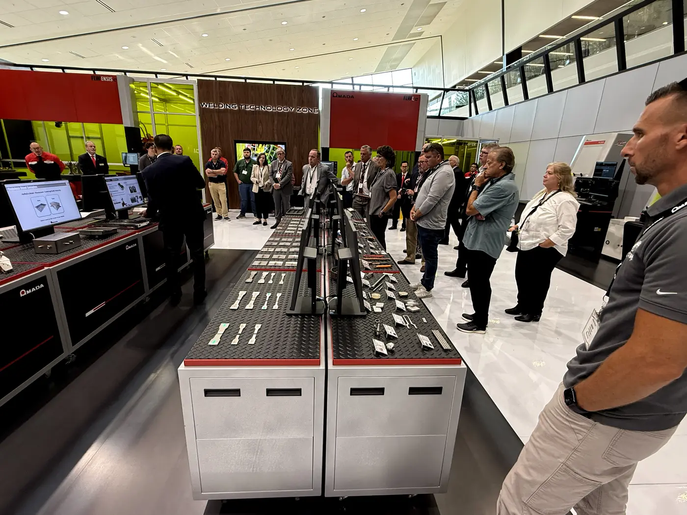 Visiteurs examinant des pièces soudées échantillons sur la table de démonstration