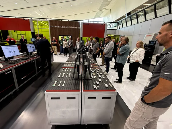 Visitors reviewing welded sample parts on the display table